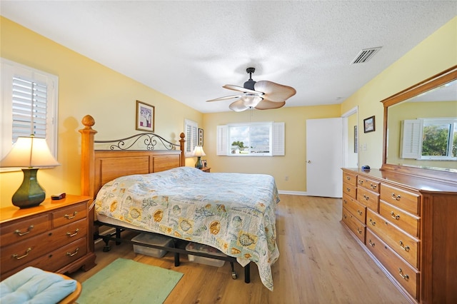 bedroom featuring a textured ceiling, light wood-type flooring, and ceiling fan