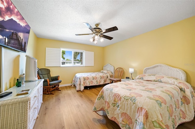 bedroom with a textured ceiling, light hardwood / wood-style floors, and ceiling fan