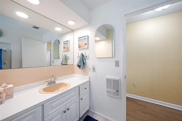 bathroom with heating unit, decorative backsplash, hardwood / wood-style floors, and vanity