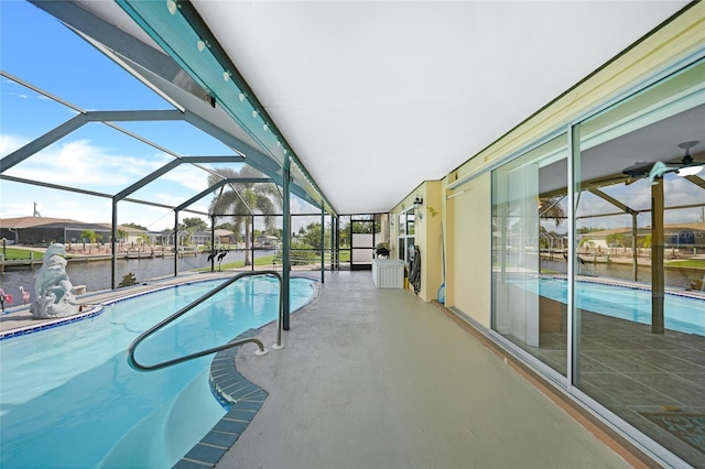 view of pool featuring glass enclosure, a water view, and a patio