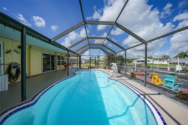 view of pool with glass enclosure and a patio