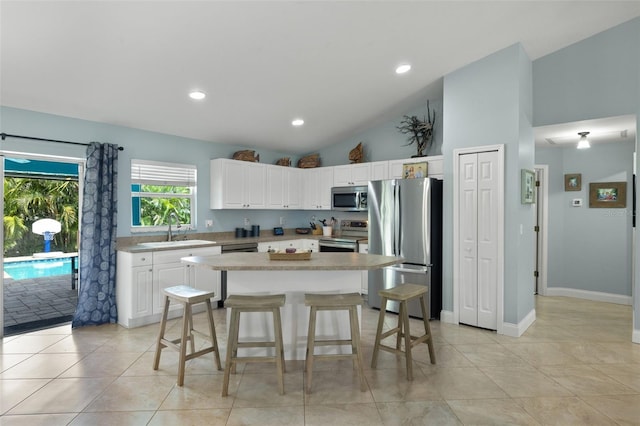 kitchen featuring white cabinetry, sink, a center island, vaulted ceiling, and appliances with stainless steel finishes