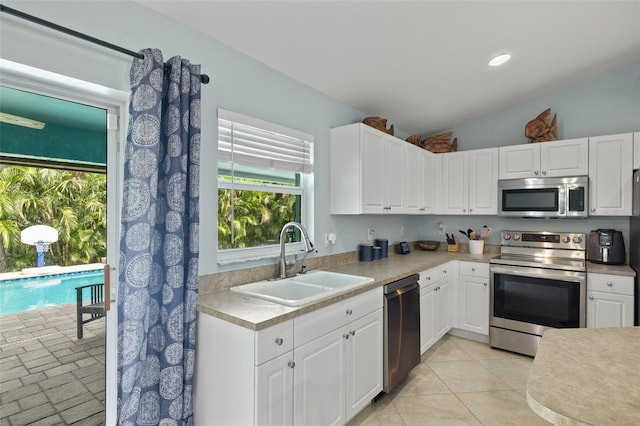 kitchen featuring white cabinets, stainless steel appliances, lofted ceiling, and sink