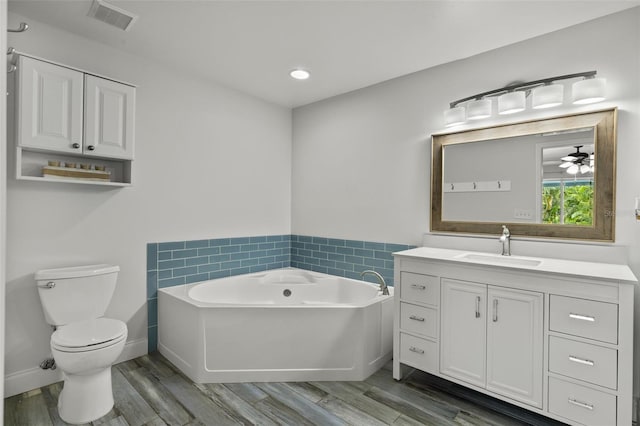 bathroom with a bathing tub, ceiling fan, wood-type flooring, toilet, and vanity