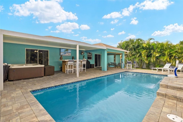 view of pool with a patio area, exterior bar, and a hot tub