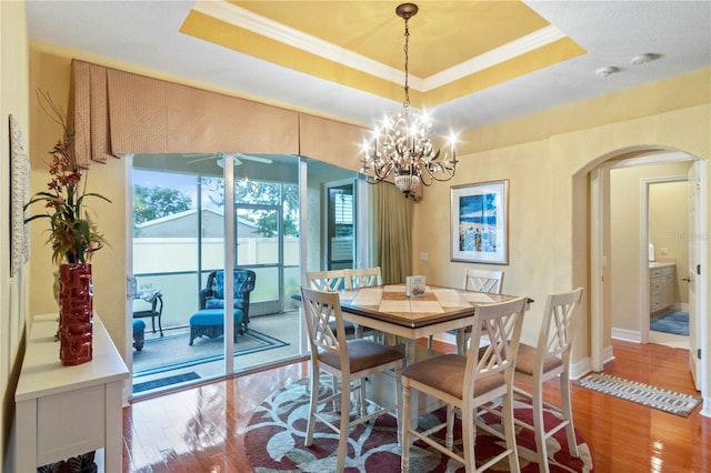 dining room featuring a notable chandelier, a tray ceiling, hardwood / wood-style flooring, and ornamental molding