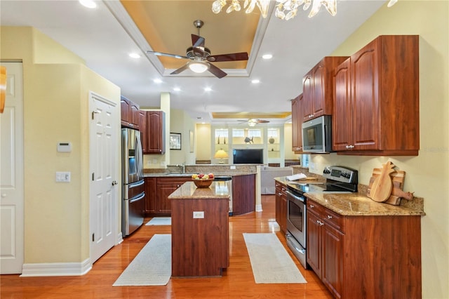 kitchen featuring light hardwood / wood-style floors, a center island, sink, ceiling fan with notable chandelier, and appliances with stainless steel finishes