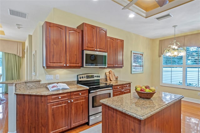 kitchen featuring light hardwood / wood-style floors, stainless steel appliances, a center island, decorative light fixtures, and a chandelier