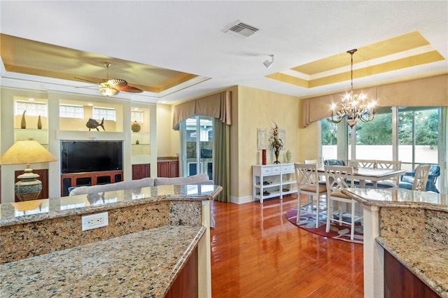 kitchen featuring ceiling fan with notable chandelier, a raised ceiling, and plenty of natural light