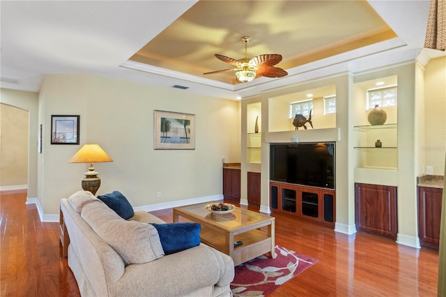 living room featuring a tray ceiling, ceiling fan, and hardwood / wood-style flooring