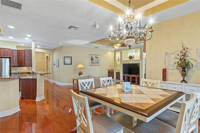 dining room featuring hardwood / wood-style flooring, a tray ceiling, and a notable chandelier