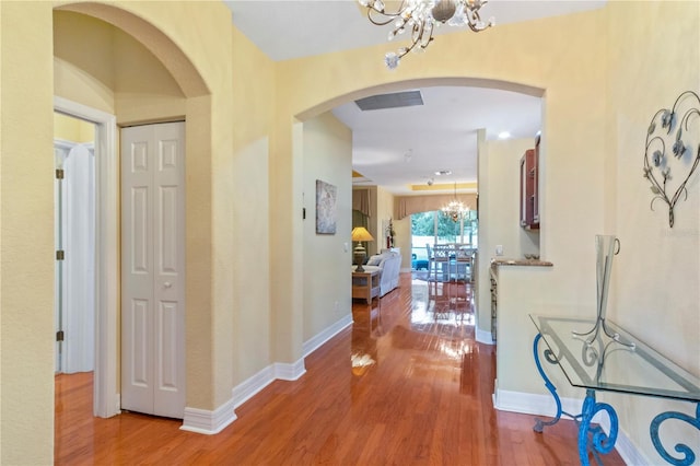 hallway with hardwood / wood-style floors and a notable chandelier