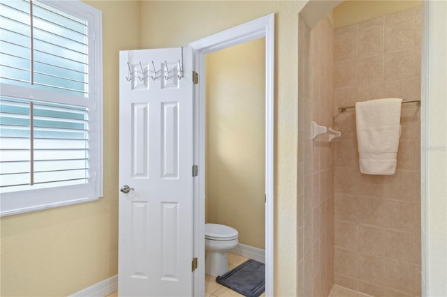 bathroom featuring tile patterned floors, plenty of natural light, toilet, and tiled shower