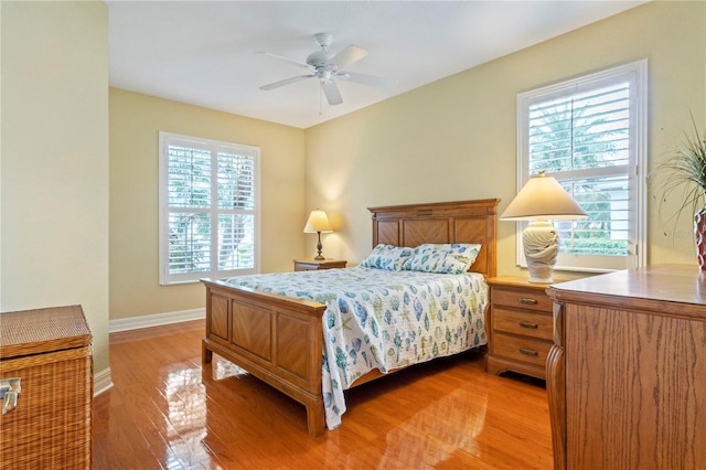 bedroom featuring multiple windows, hardwood / wood-style floors, and ceiling fan