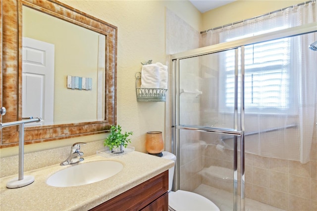 bathroom featuring vanity, a shower with shower door, and toilet