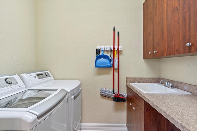 clothes washing area with washing machine and clothes dryer, cabinets, and sink