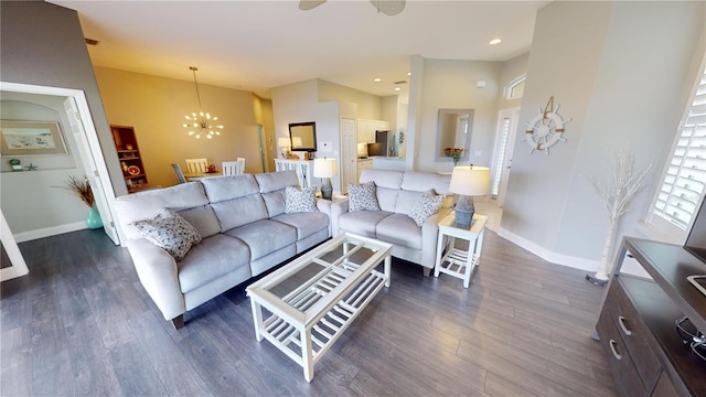 living room with ceiling fan with notable chandelier and dark hardwood / wood-style floors