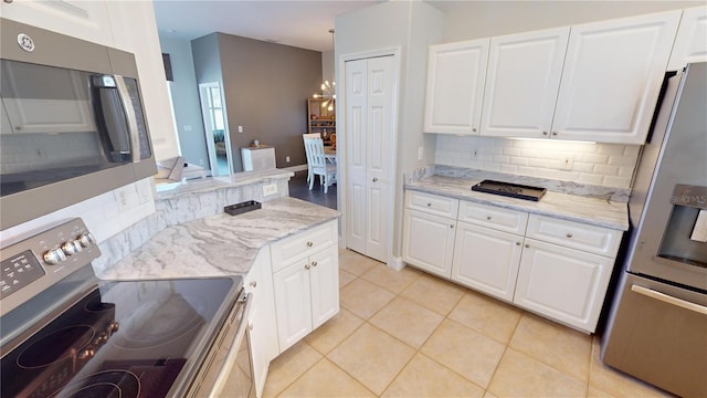 kitchen with appliances with stainless steel finishes, decorative backsplash, white cabinetry, and light tile patterned floors