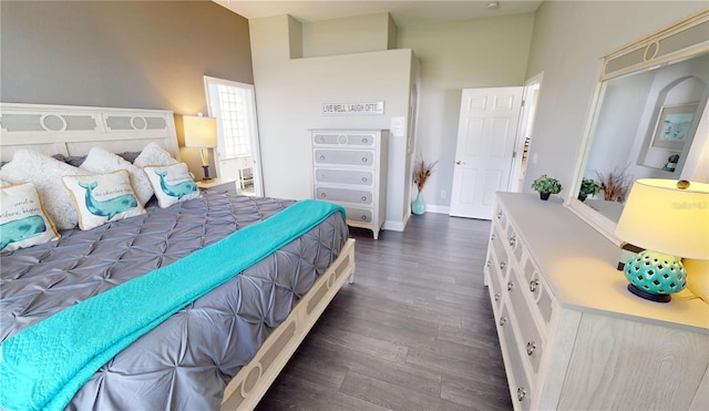 bedroom with a high ceiling and dark hardwood / wood-style flooring