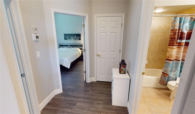 bathroom featuring toilet, shower / bath combo with shower curtain, and hardwood / wood-style floors