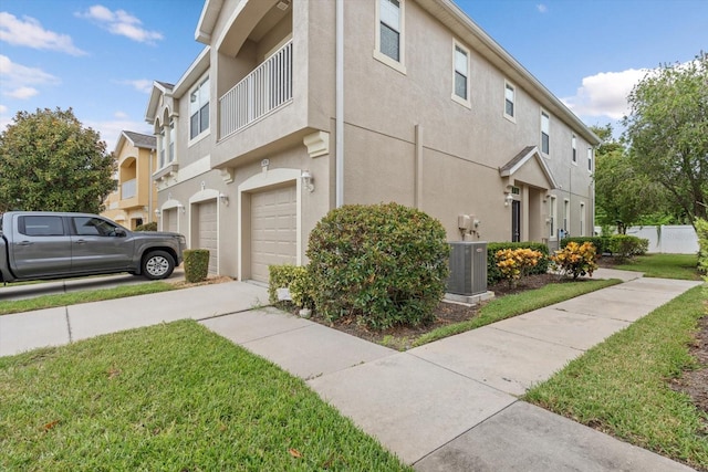 view of property exterior with a balcony, a garage, central air condition unit, and a yard