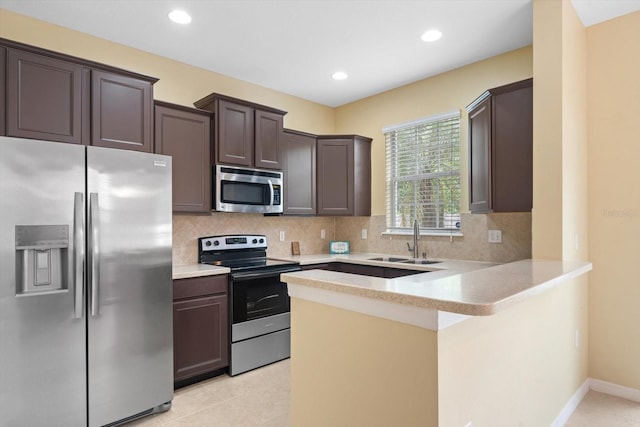 kitchen with stainless steel appliances, backsplash, kitchen peninsula, and sink