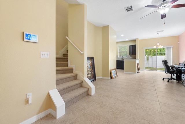 stairs featuring ceiling fan with notable chandelier, tile patterned floors, and sink