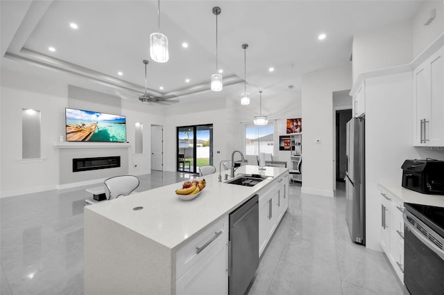 kitchen featuring a kitchen island with sink, sink, stainless steel appliances, and white cabinetry