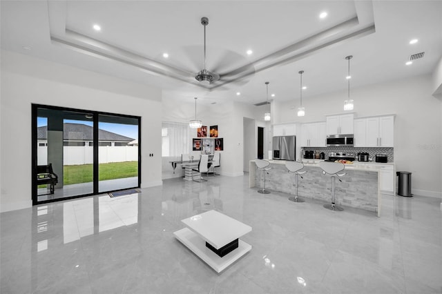 living room featuring ceiling fan and a raised ceiling