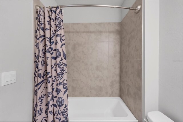 bathroom with toilet and shower / bath combo with shower curtain