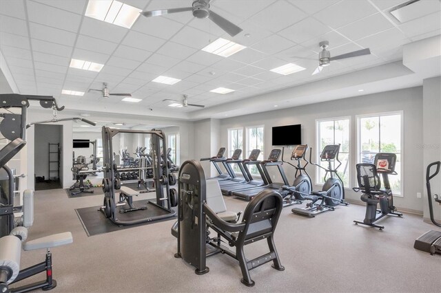 workout area with a paneled ceiling, ceiling fan, and baseboards