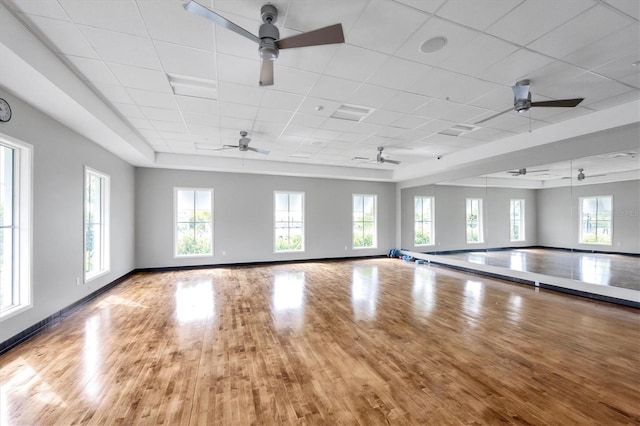 interior space with light wood finished floors, a drop ceiling, a wealth of natural light, and baseboards