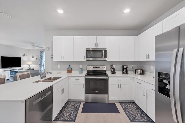 kitchen featuring light countertops, appliances with stainless steel finishes, a sink, and white cabinets