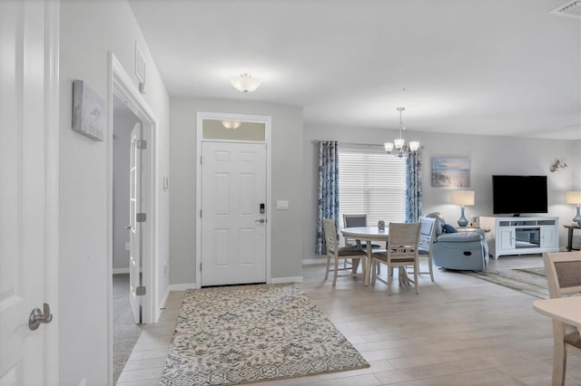 foyer with light wood-type flooring, baseboards, visible vents, and a notable chandelier