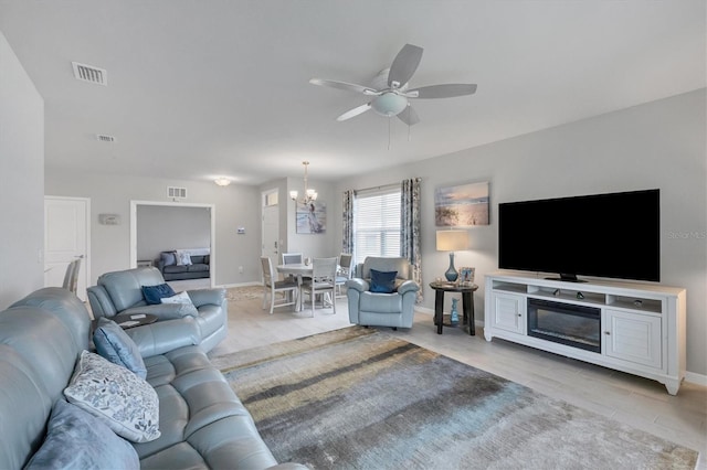 living area with visible vents, baseboards, and ceiling fan with notable chandelier