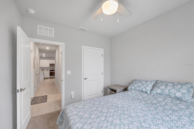 bedroom with ceiling fan, light wood-type flooring, and visible vents