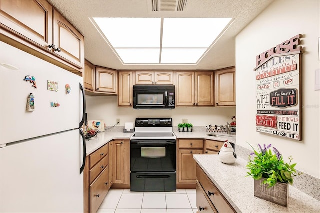 kitchen featuring light stone counters, light tile patterned floors, black appliances, light brown cabinetry, and sink