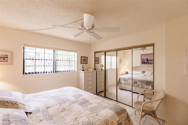 tiled bedroom featuring ceiling fan, a textured ceiling, and a closet