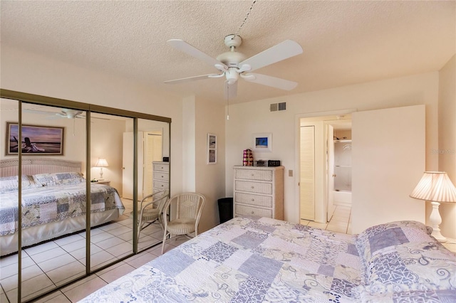 bedroom featuring a closet, ceiling fan, light tile patterned floors, and a textured ceiling