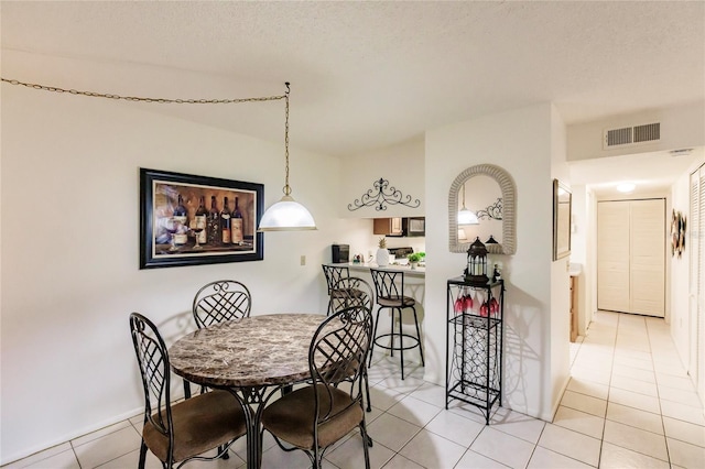 dining area with a textured ceiling and light tile patterned floors