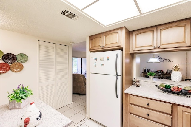 kitchen featuring light brown cabinets, white refrigerator, and light tile patterned floors