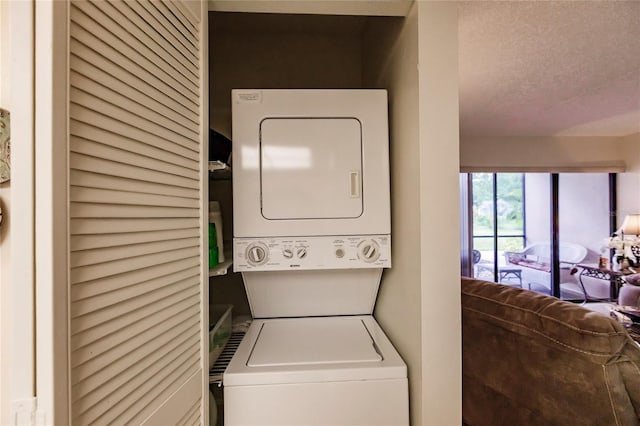 laundry area with a textured ceiling and stacked washer / dryer