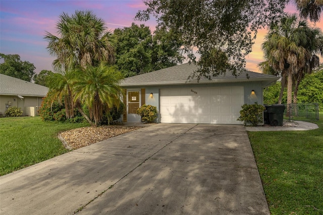 ranch-style home with a garage and a lawn