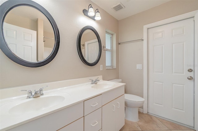 bathroom with toilet, vanity, and tile patterned floors