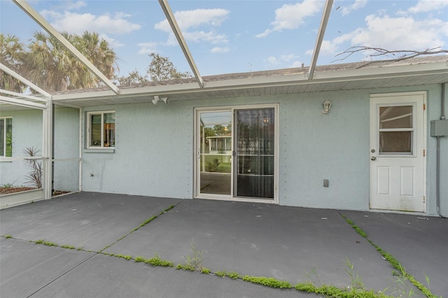 back of property featuring a patio area and glass enclosure