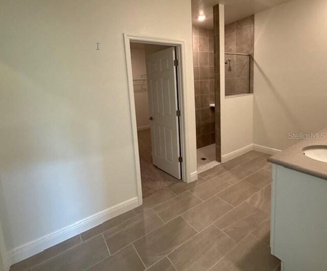 bathroom featuring a tile shower, tile patterned floors, and vanity