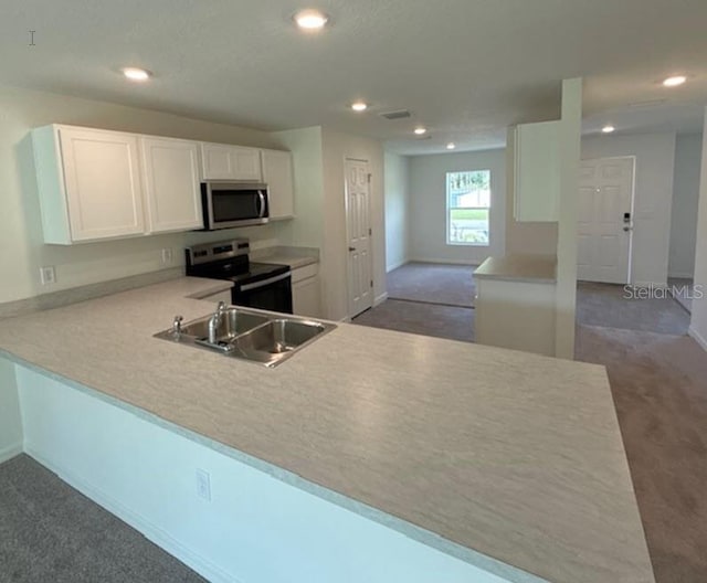 kitchen with dark carpet, appliances with stainless steel finishes, kitchen peninsula, and white cabinetry