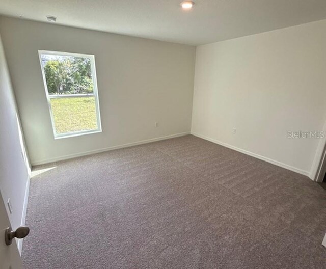 spare room featuring dark carpet