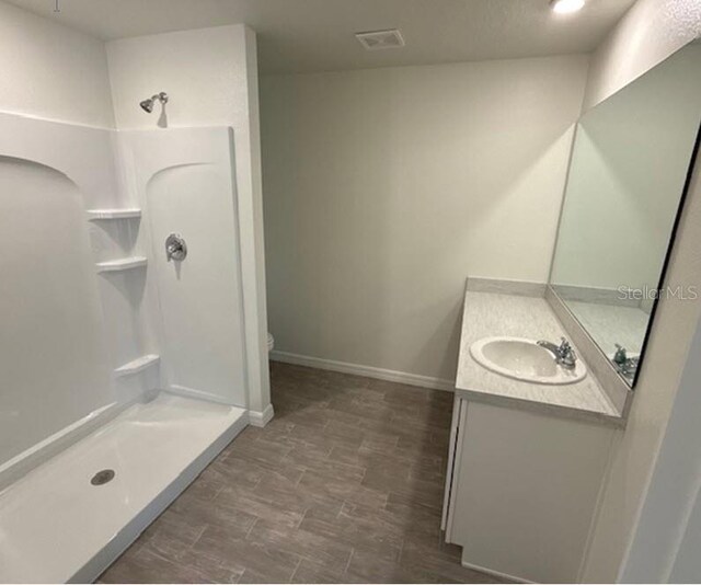 bathroom with walk in shower, vanity, and toilet