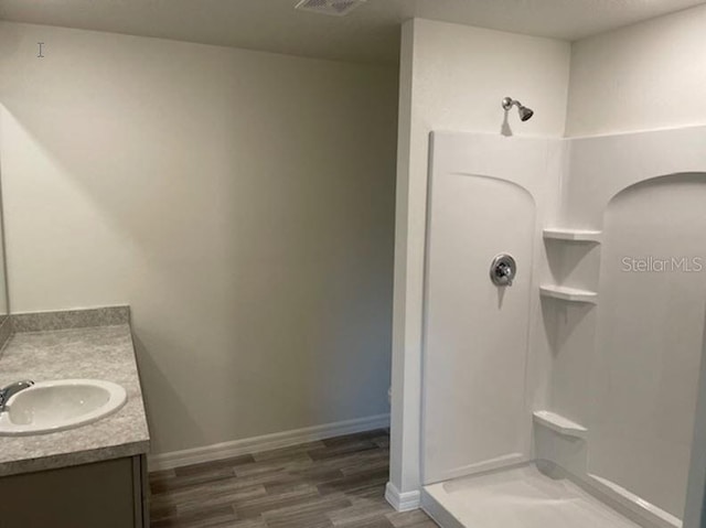 bathroom with walk in shower, vanity, and hardwood / wood-style floors